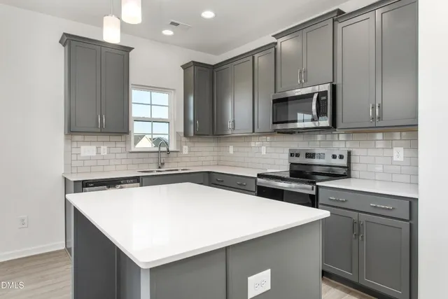 a kitchen with stainless steel appliances a sink a stove a microwave a sink and cabinets