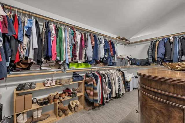 a view of walk in closet with clothes and shoes