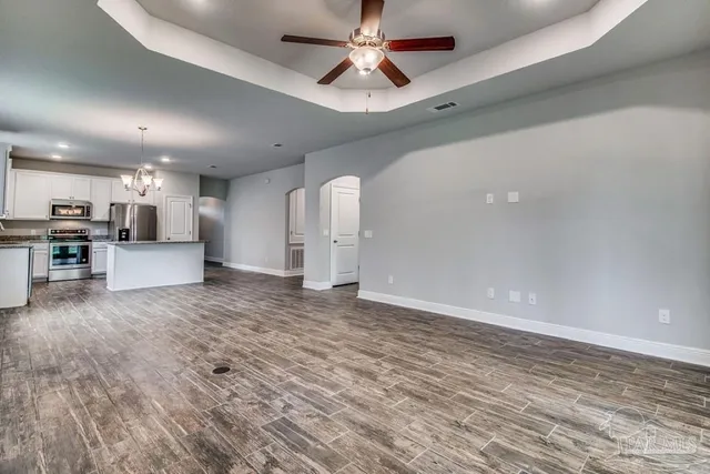 a view of kitchen and empty room with wooden floor