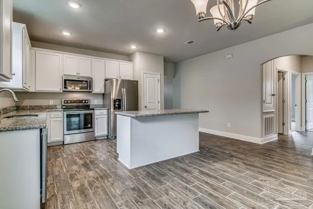 a kitchen with granite countertop a refrigerator and a stove top oven
