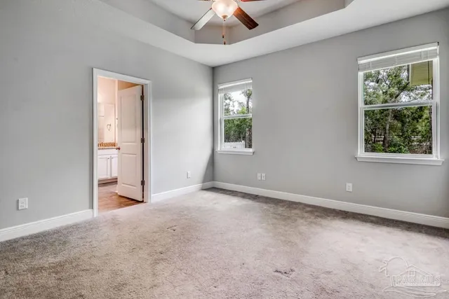 an empty room with windows and ceiling fan
