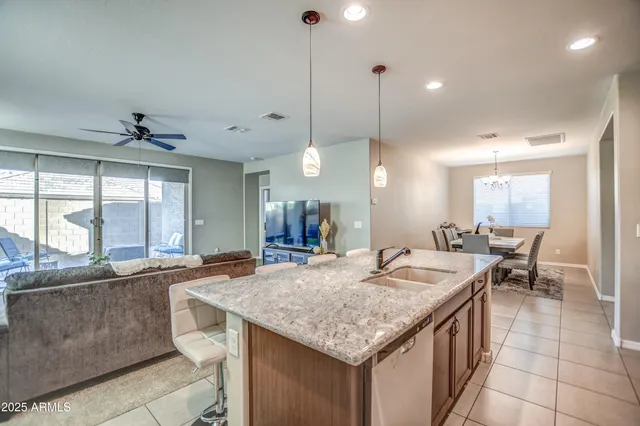 a kitchen with stainless steel appliances granite countertop a stove top oven a sink dishwasher and a refrigerator with wooden cabinets