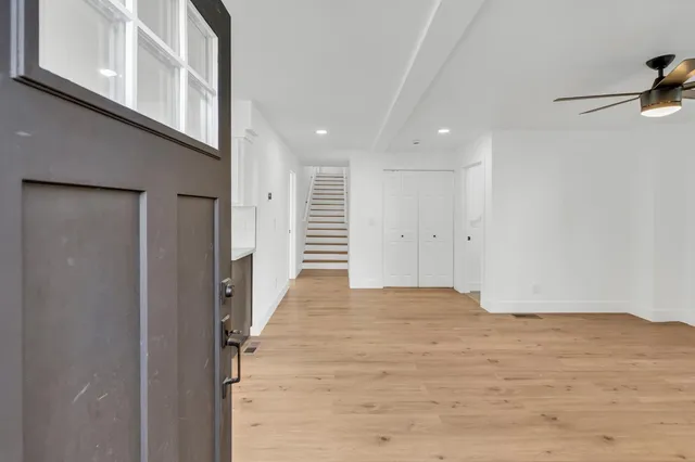 an empty room with wooden floor chandelier fan and windows