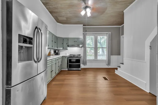 a kitchen with stainless steel appliances granite countertop a refrigerator a sink dishwasher a stove and a refrigerator with wooden floor