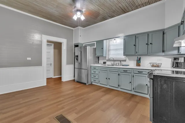 a kitchen with stainless steel appliances granite countertop a stove a sink dishwasher and a refrigerator with wooden floor