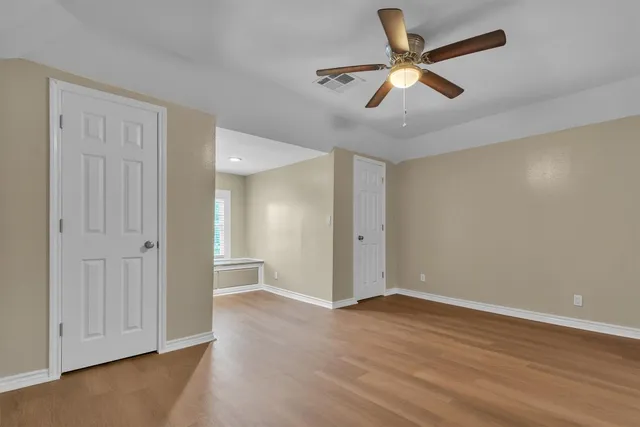 an empty room with wooden floor and ceiling fan