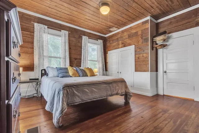 a bedroom with a bed and a large window with wooden floor