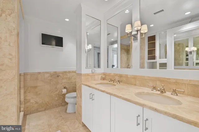 a bathroom with a double vanity sink mirror and toilet