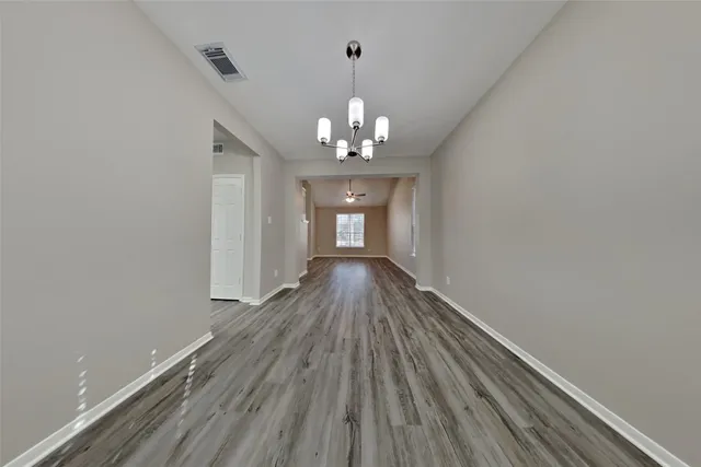 a view of a hallway with wooden floor and a chandelier