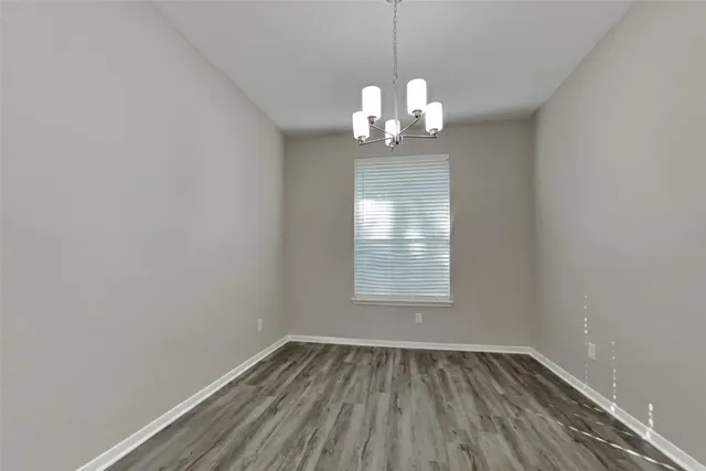 an empty room with wooden floor chandelier and window