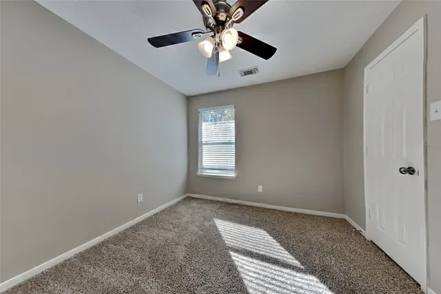 a view of an empty room with window and a ceiling fan