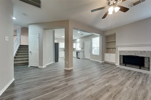 a view of an empty room with wooden floor fireplace and a window