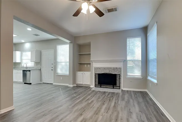 a view of an empty room with wooden floor fireplace and a window