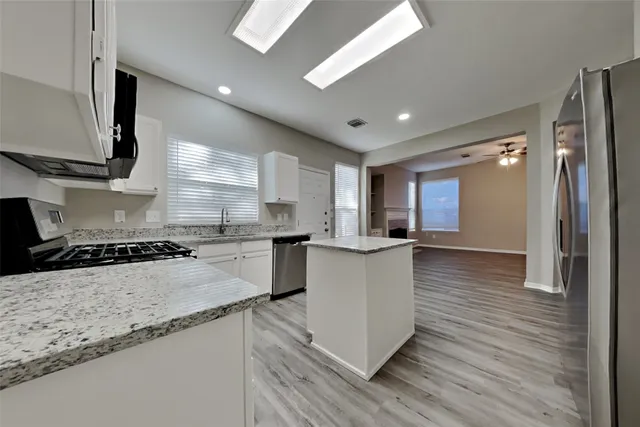 a kitchen with stainless steel appliances granite countertop a sink a stove and a refrigerator