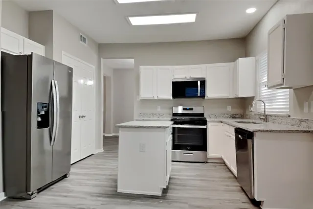 a kitchen with stainless steel appliances a stove refrigerator sink and microwave