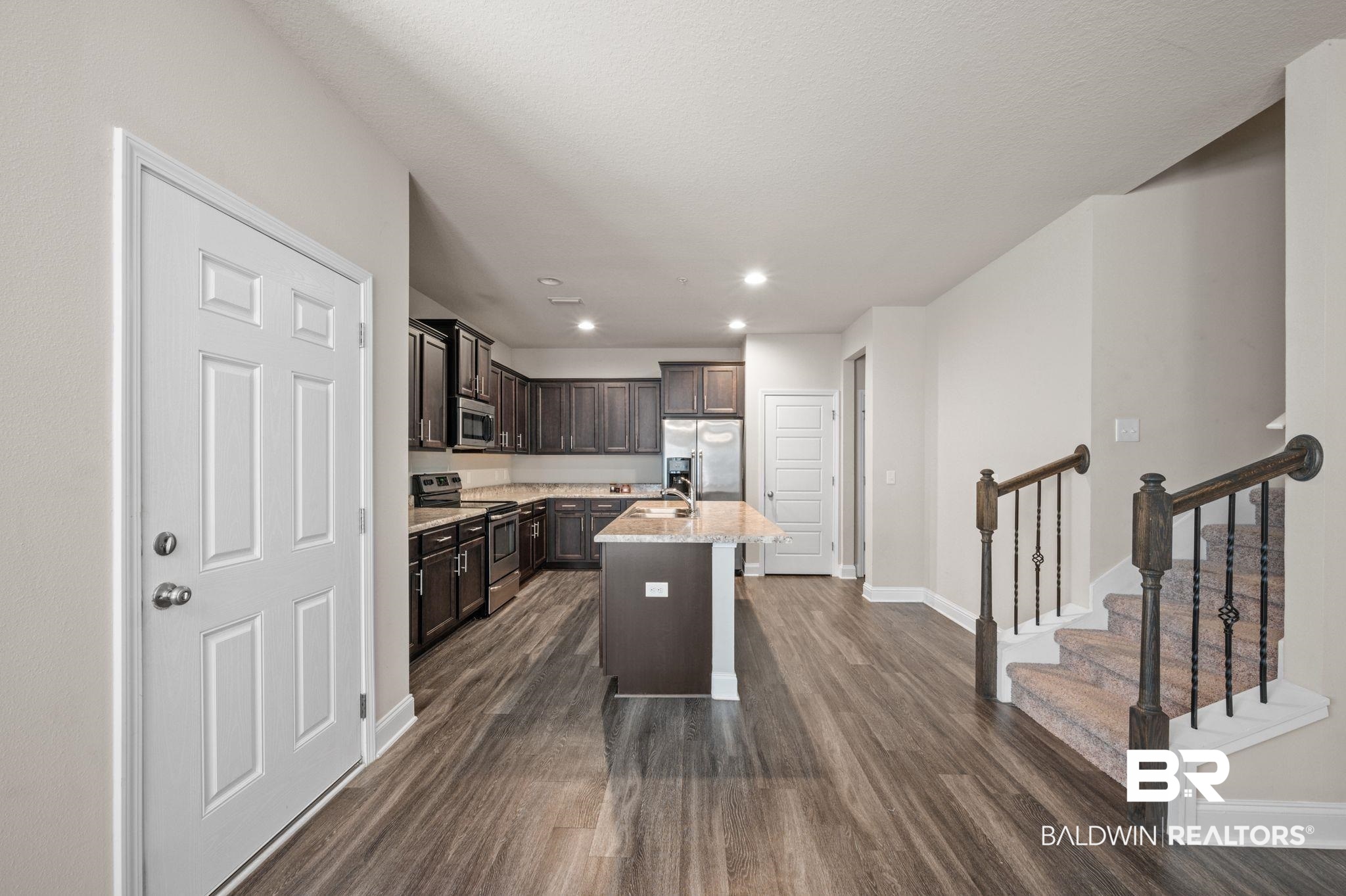 6903 Spaniel Drive, Unit B Spanish Fort, AL 36527 - Photo 6 of 28 Kitchen featuring dark brown cabinets, appliances with stainless steel finishes, dark wood-style flooring, and a center island with sink
