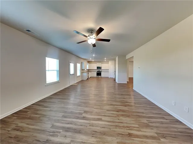 a view of empty room with wooden floor and ceiling fan