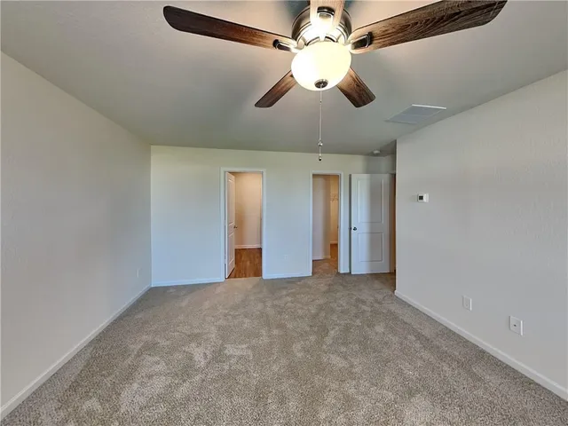 a view of an empty room with a chandelier fan