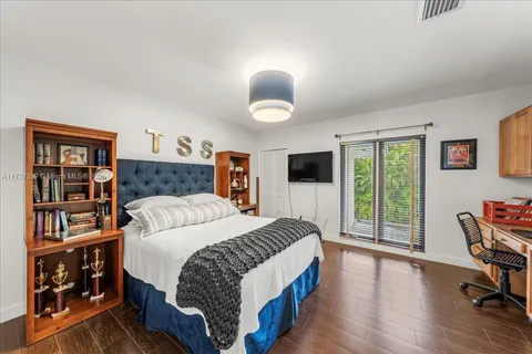 a bedroom with a bed a bookshelf and a flat screen tv
