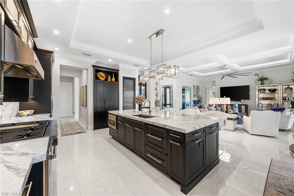 12499 Twin Eagles Boulevard Naples, FL 34120 - Photo 15 of 50 a living room with stainless steel appliances kitchen island granite countertop a stove top oven a sink dishwasher and a fireplace with wooden floor