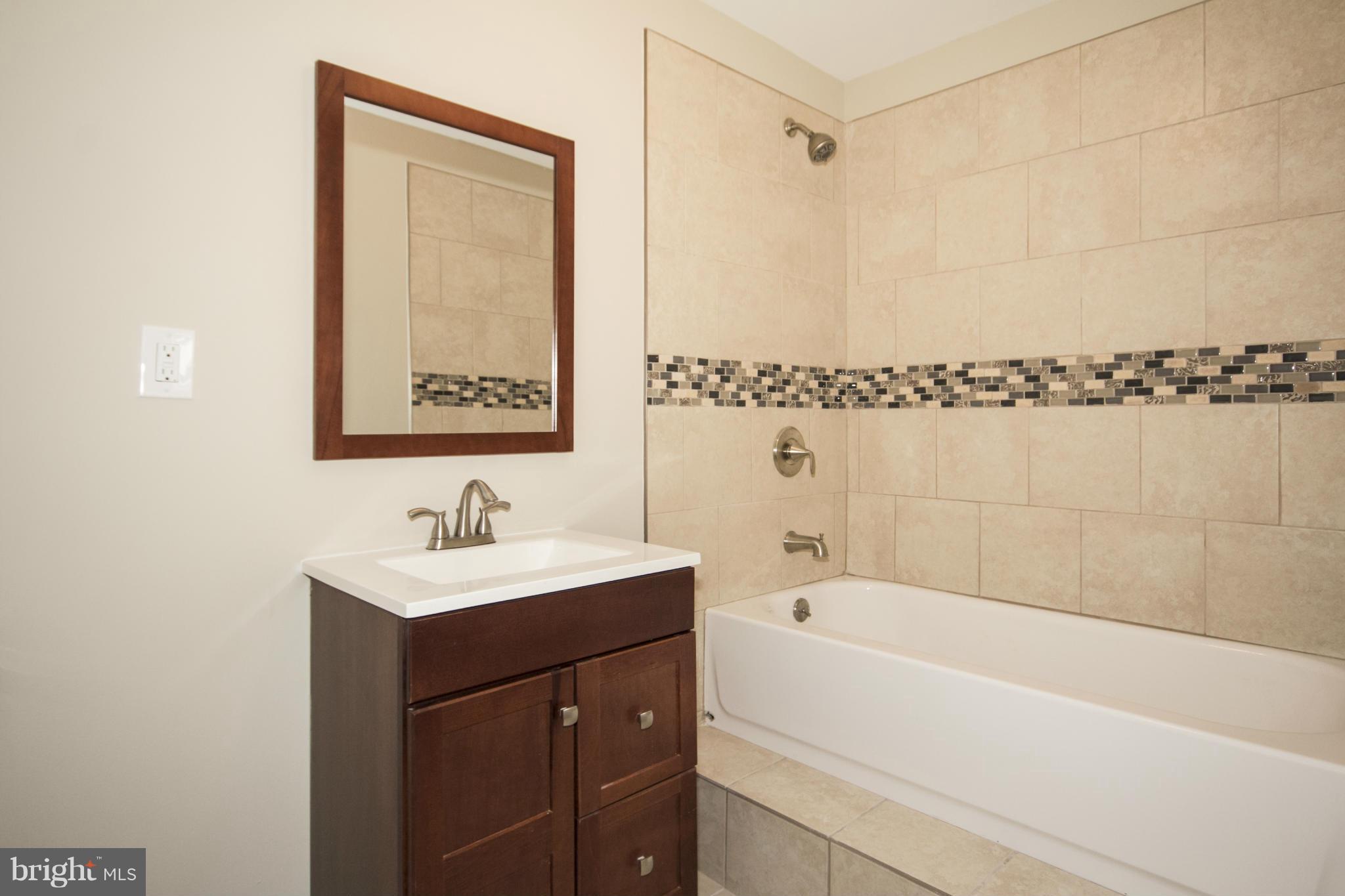 6701 Longhill Road Baltimore, MD 21207 - Photo 22 of 27 a bathroom with a bathtub a shower a sink and a window
