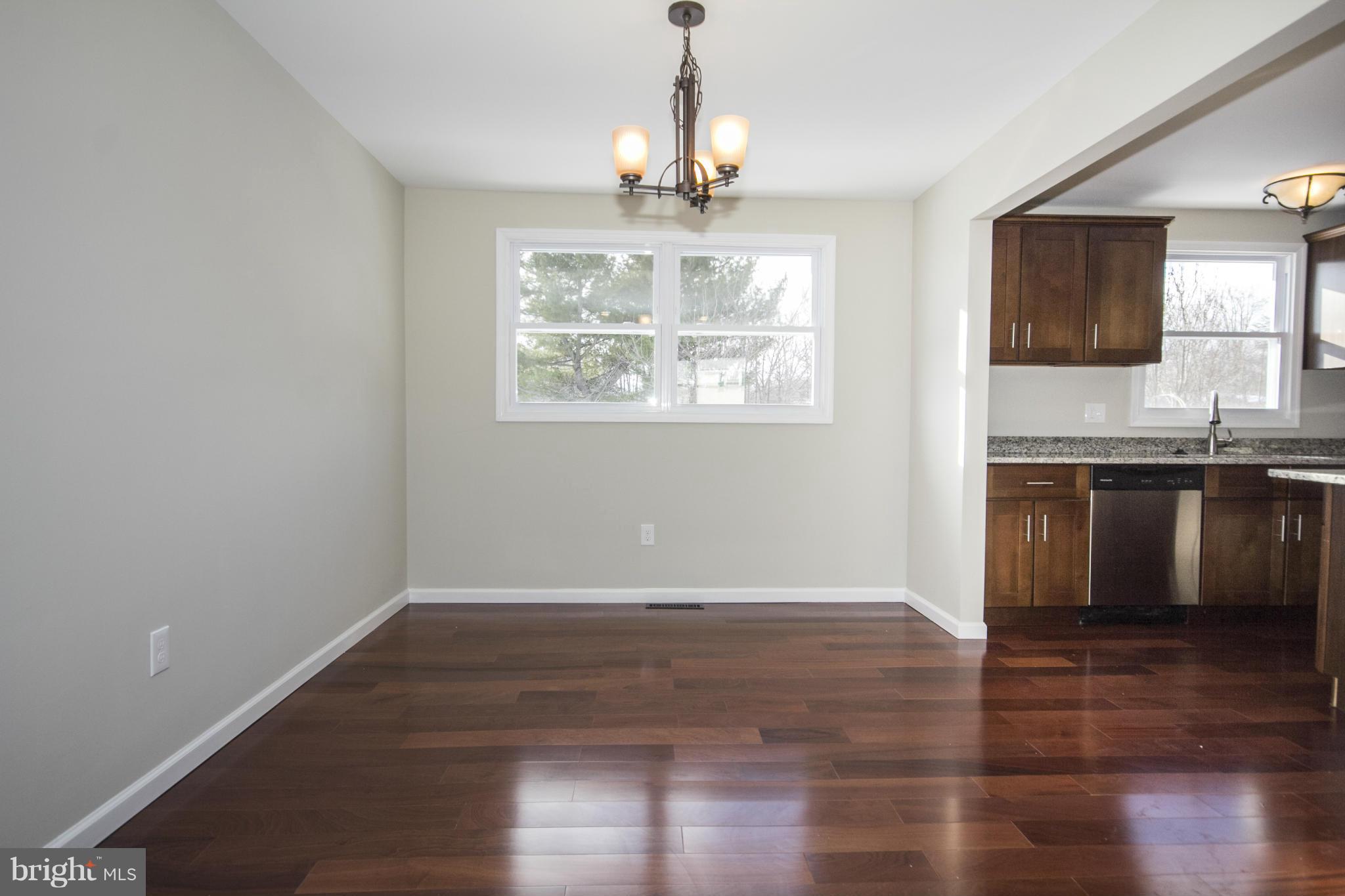 6701 Longhill Road Baltimore, MD 21207 - Photo 5 of 27 an empty room with wooden floor chandelier and windows