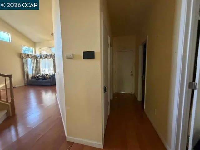 a view of a hallway with wooden floor and a living room