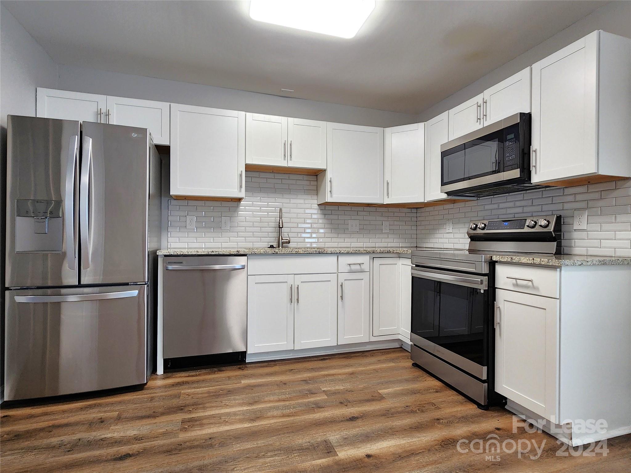 407 Spring Street Northwest, Unit 407 Concord, NC 28025 - Photo 1 of 19 a kitchen with stainless steel appliances granite countertop a refrigerator stove a sink and a microwave
