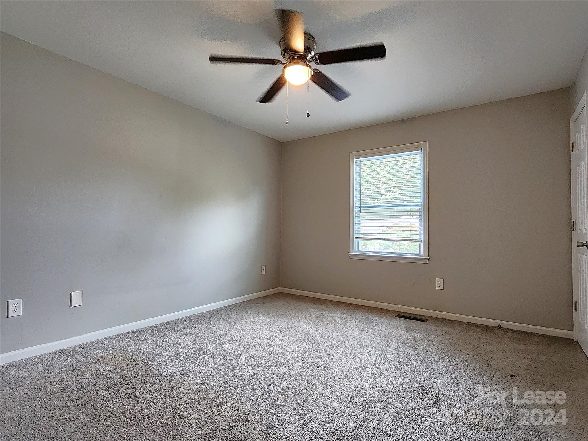 407 Spring Street Northwest, Unit 407 Concord, NC 28025 - Photo 12 of 19 an empty room with windows and fan