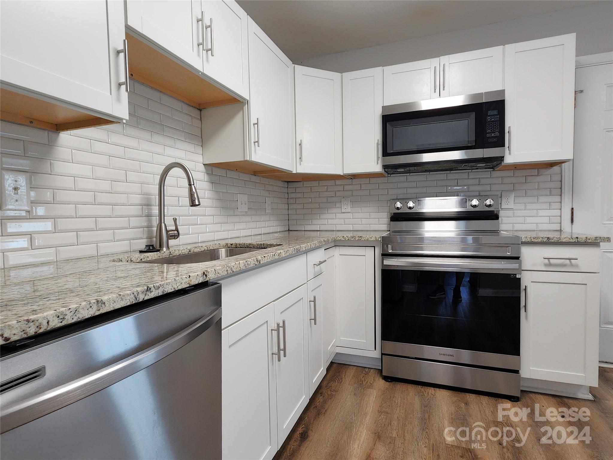 407 Spring Street Northwest, Unit 407 Concord, NC 28025 - Photo 5 of 19 a kitchen with stainless steel appliances granite countertop a sink dishwasher a stove and a microwave oven with granite countertops