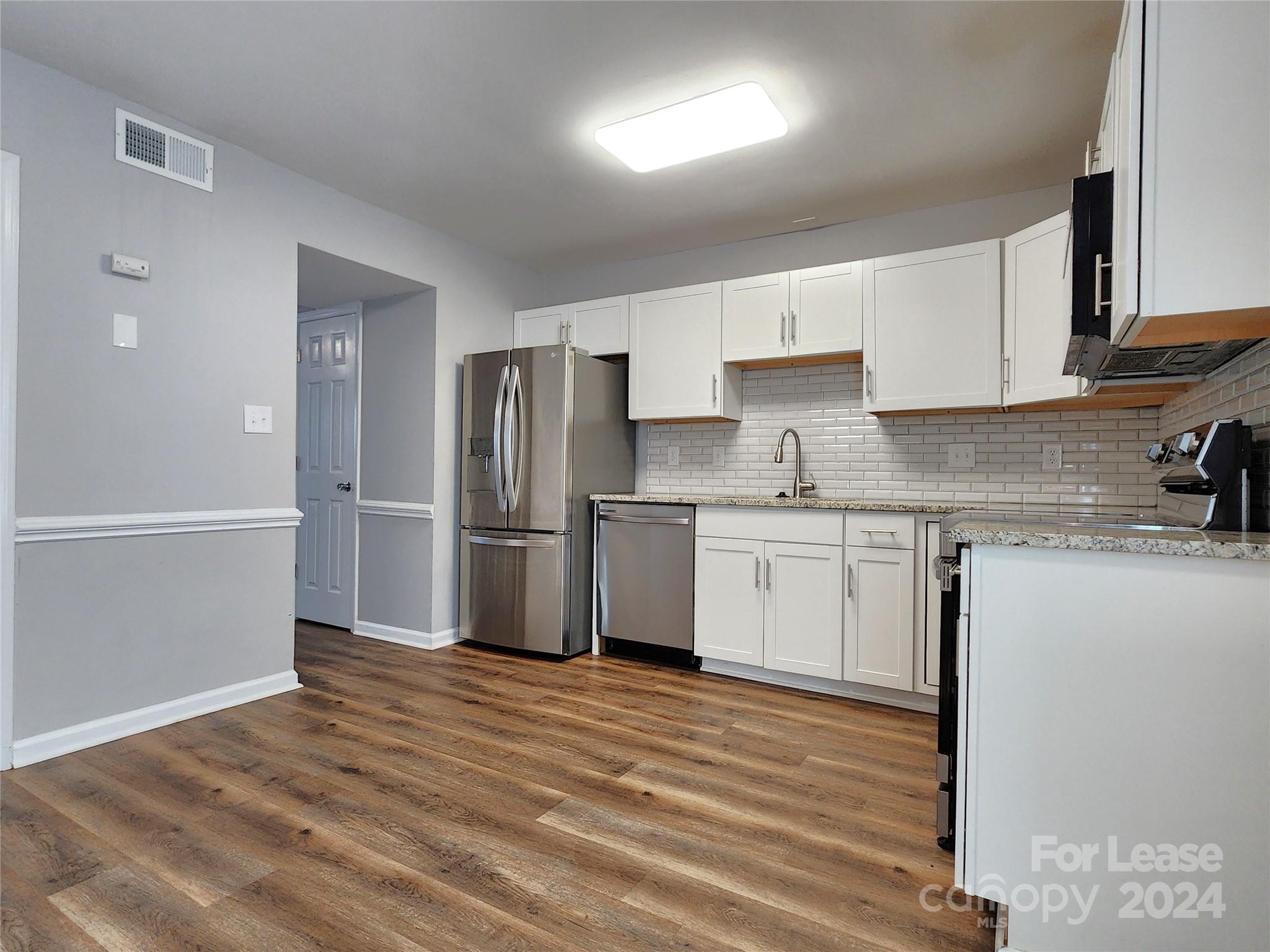 407 Spring Street Northwest, Unit 407 Concord, NC 28025 - Photo 6 of 19 a kitchen with granite countertop white cabinets and stainless steel appliances