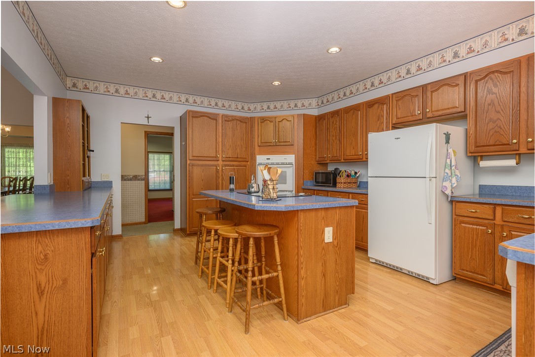 8745 Broadview Road Broadview Heights, OH 44147 - Photo 7 of 49 Kitchen featuring extensive wood cabinetry, wood-finish flooring, recessed lighting, a central island with countertop seating, and blue laminate countertops