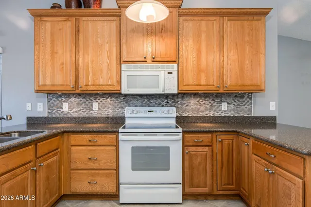 a kitchen with granite countertop wooden cabinets and white appliances