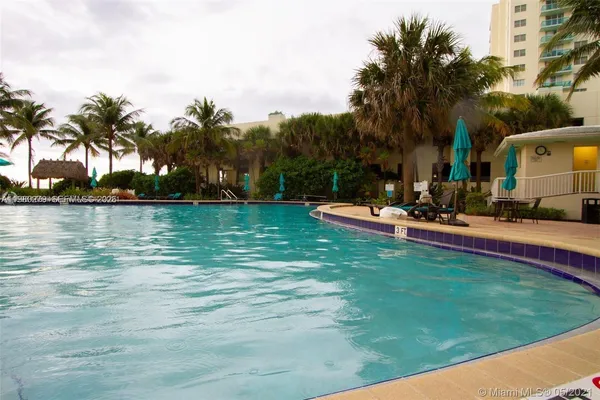 a view of a swimming pool with a yard and palm trees