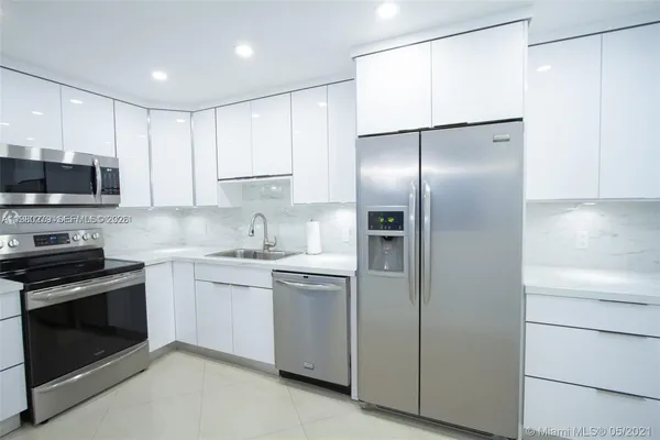 a kitchen with stainless steel appliances granite countertop a refrigerator a stove and a sink with wooden floor