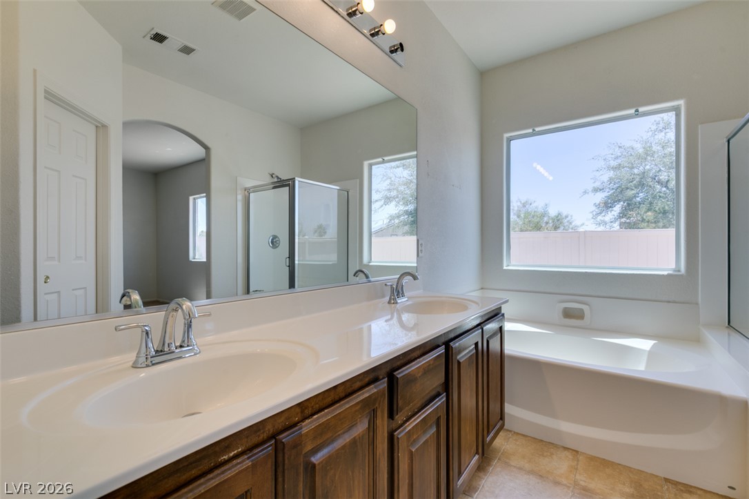 5150 Riverside Run Court North Las Vegas, NV 89081 - Photo 42 of 50 A well-lit primary bathroom featuring dual vanities, a separate tub, and a shower, providing a relaxing oasis.