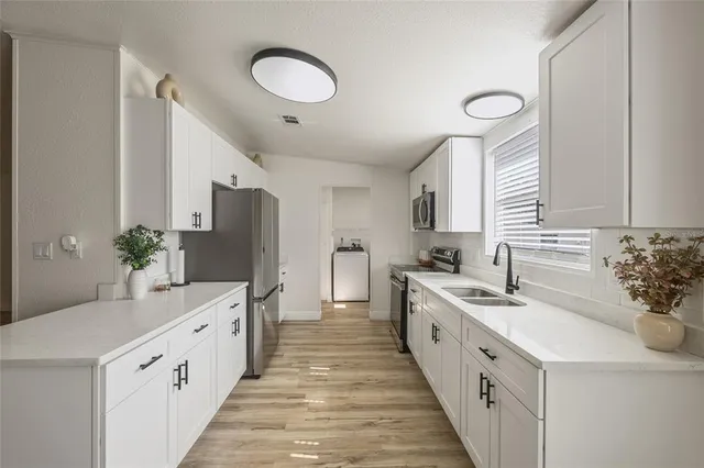 a large white kitchen with a double vanity sink and a refrigerator