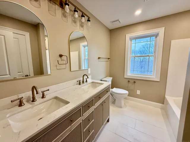 a bathroom with a granite countertop double vanity sink a mirror and a