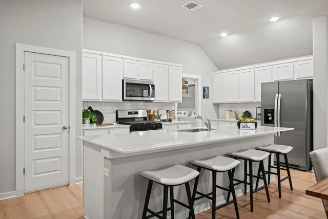 a kitchen with kitchen island a refrigerator stove microwave and cabinets