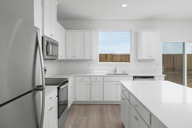 a kitchen with cabinets appliances a sink and a window