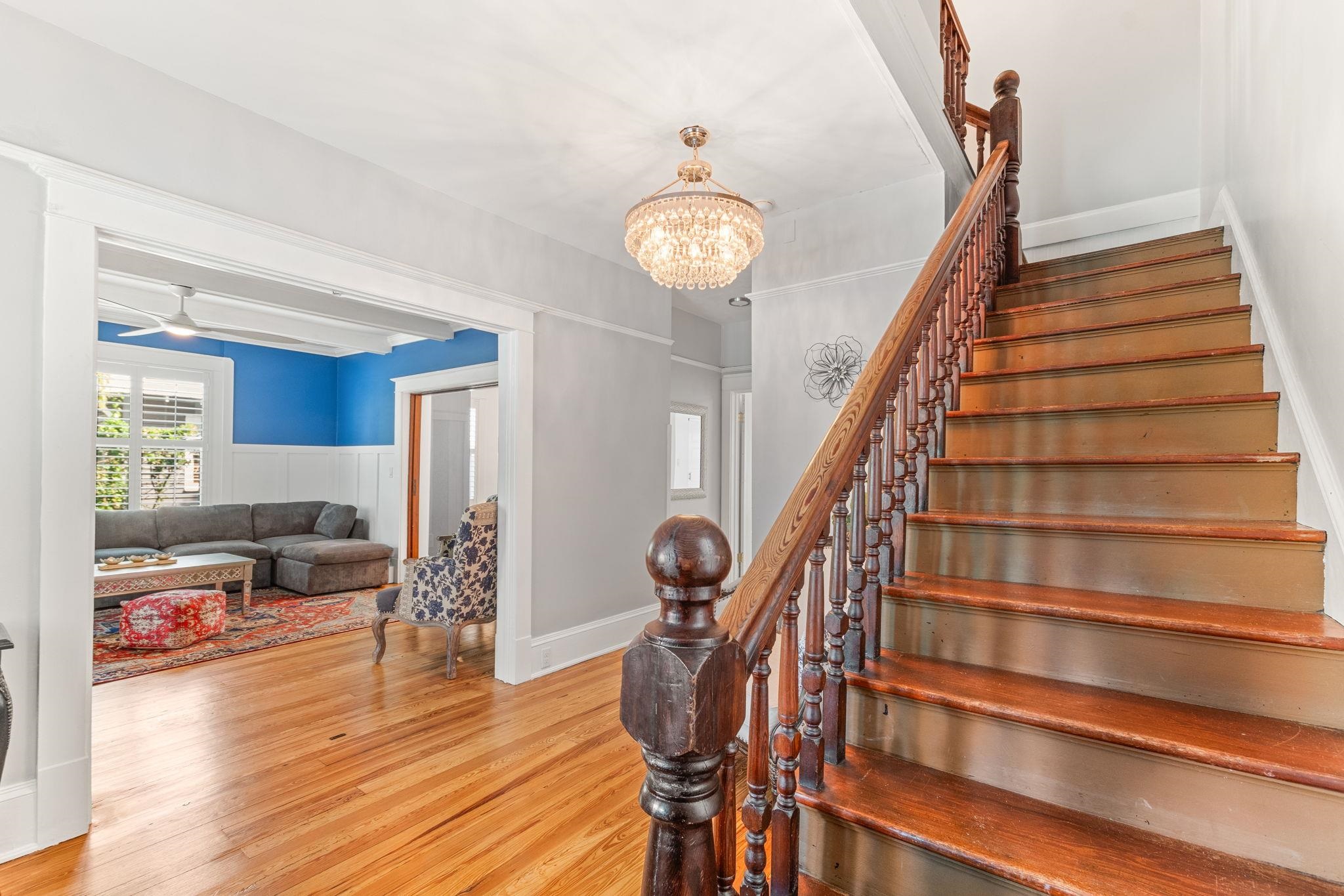 21 Saragossa Street St. Augustine, FL 32084 - Photo 33 of 66 Staircase featuring wood finished floors, a chandelier, wainscoting, and a ceiling fan