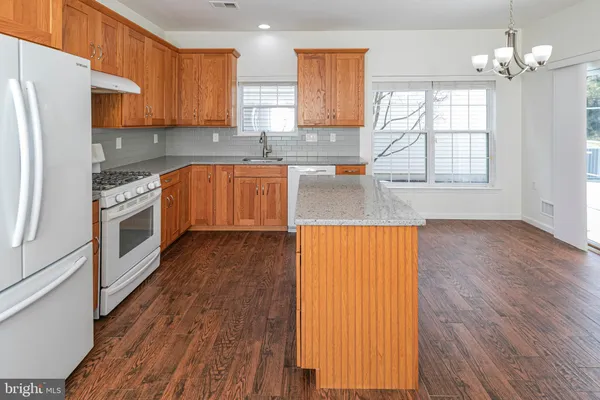 a kitchen with stainless steel appliances granite countertop wooden cabinets a window and a sink