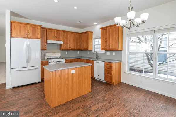 a kitchen with stainless steel appliances granite countertop a stove a sink dishwasher a refrigerator and a dining table with wooden floor