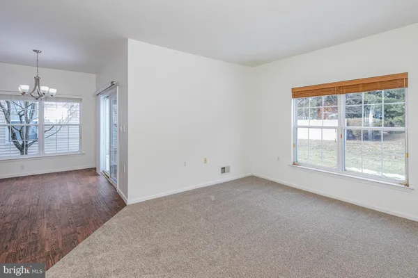 an empty room with chandelier fan and windows