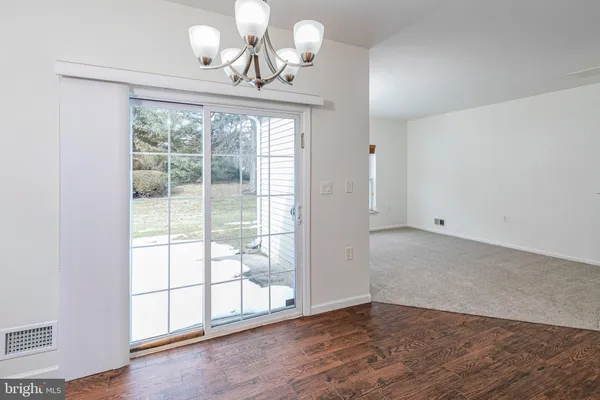 an empty room with wooden floor chandelier and windows