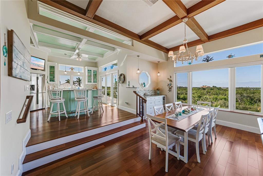 125 Burns Road Terra Ceia, FL 34250 - Photo 16 of 90 a dining room with wooden floor a chandelier a glass table and chairs