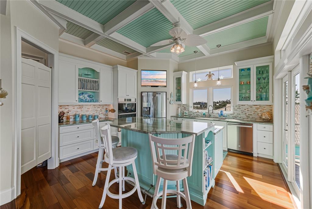 125 Burns Road Terra Ceia, FL 34250 - Photo 17 of 90 a kitchen with stainless steel appliances kitchen island granite countertop a refrigerator a stove a dining table and chairs with wooden floor