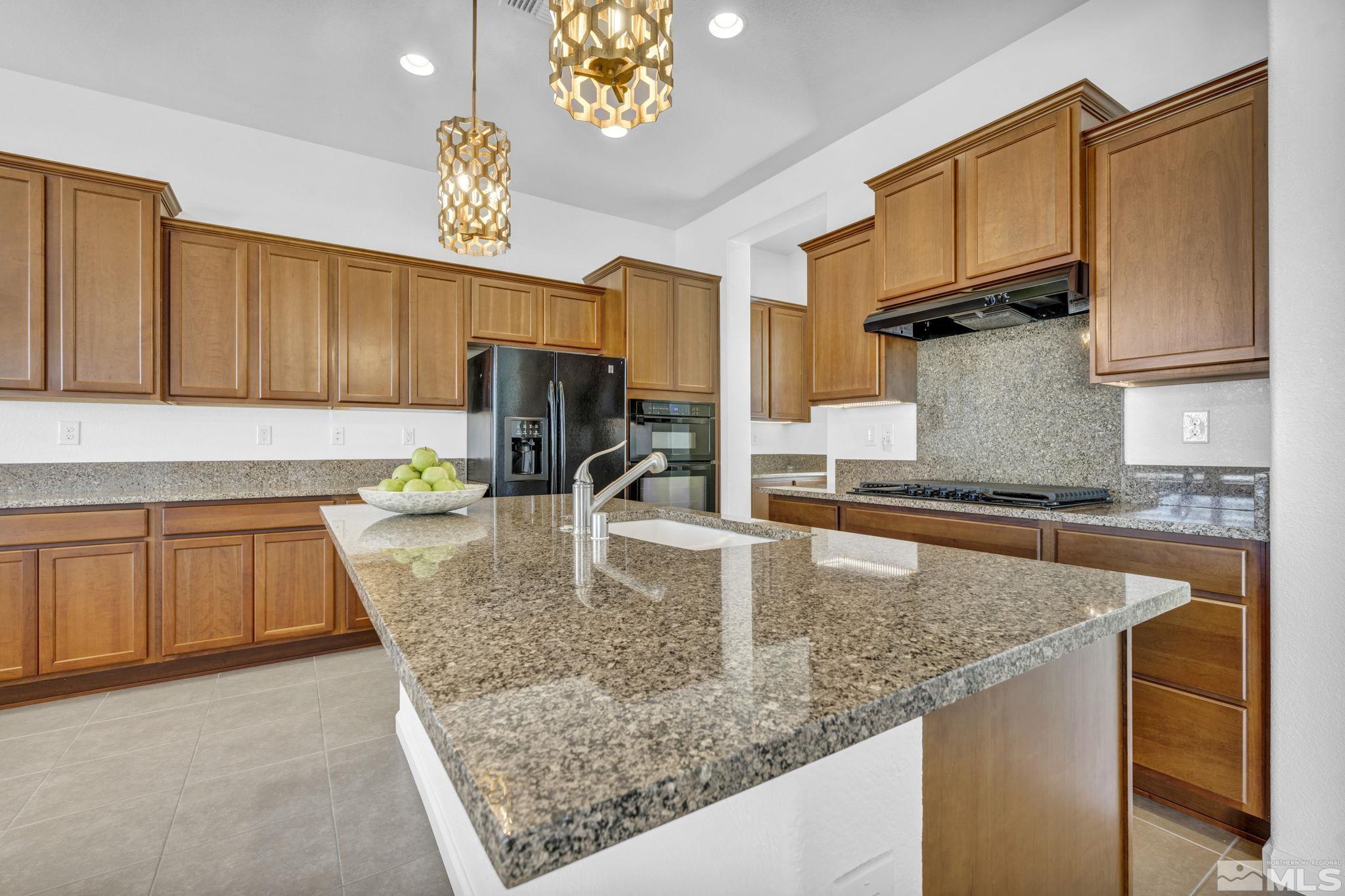9825 Hafflinger Lane Reno, NV 89521 - Photo 12 of 39 a kitchen with kitchen island granite countertop a sink a counter top space and cabinets
