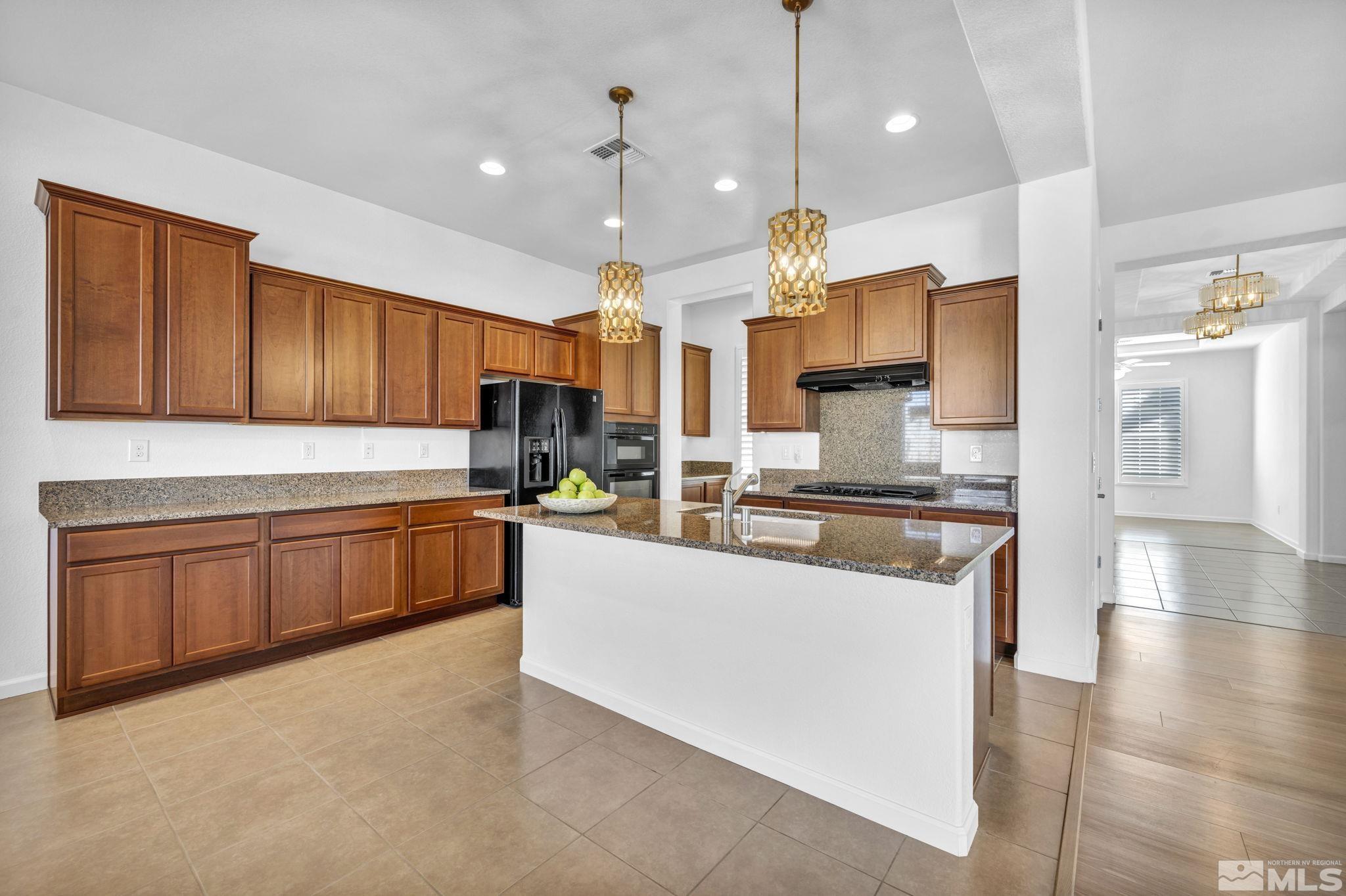 9825 Hafflinger Lane Reno, NV 89521 - Photo 8 of 39 a kitchen with stainless steel appliances granite countertop wooden cabinets a stove a sink dishwasher and a refrigerator with wooden floor