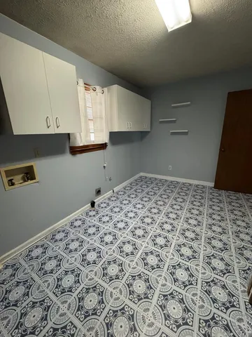 an empty room with windows cabinet and fireplace